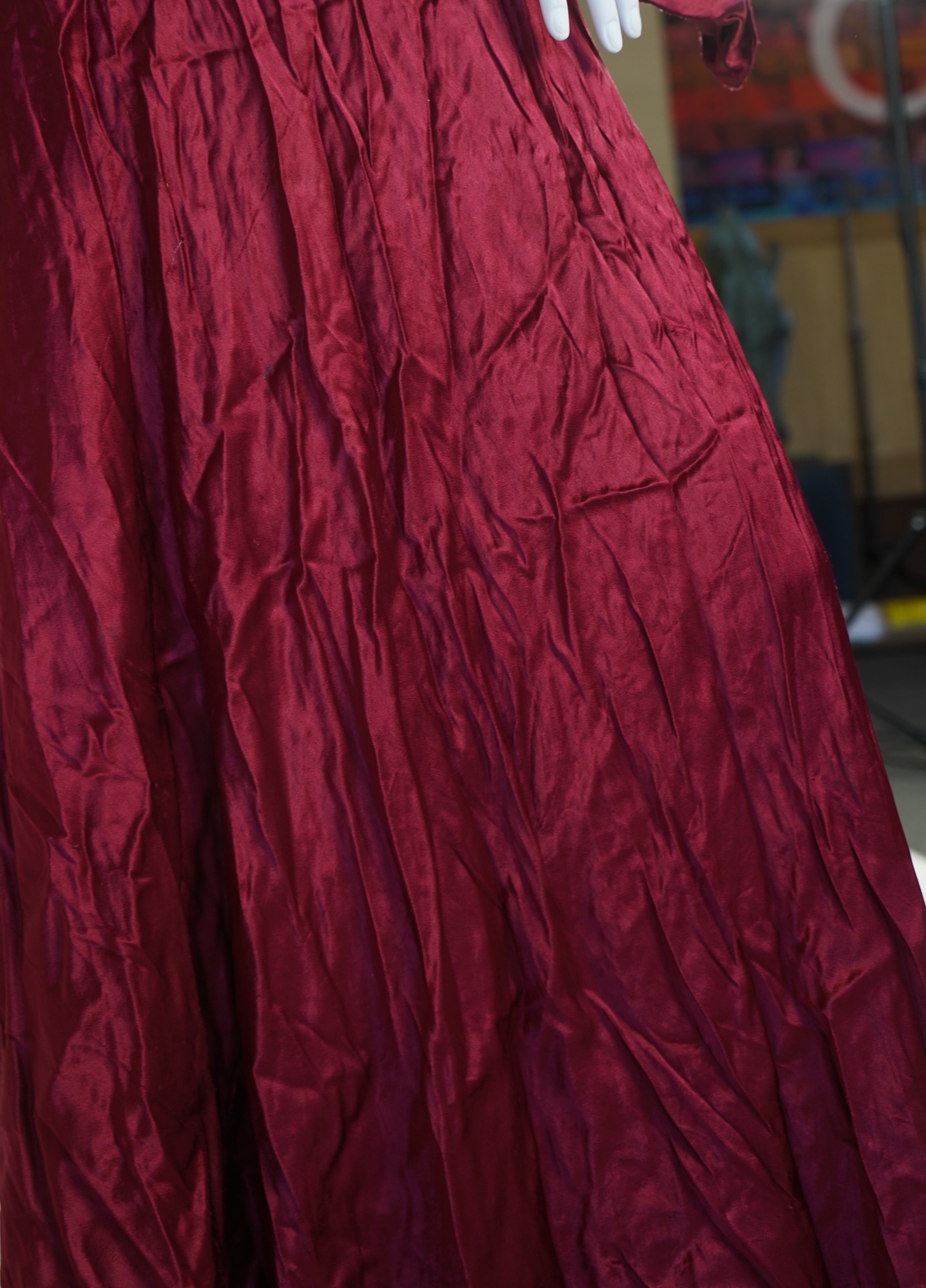 A 1920’s light green silk evening cape with hand batik borders and label: Tito de Canival Mode, together with a navy ladies two piece suit and a maroon satin evening dress. Cape 100cm long. Condition - cape good, navy tw